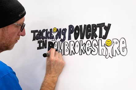 Man in hat drawing bubble writing saying tackling poverty in Pembrokeshire