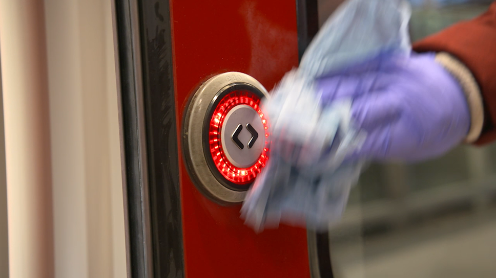 Cleaning train door button on a Greater Anglia train