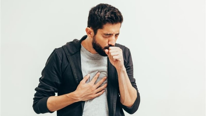 TB awareness: Image shows a man with coughing into one hand, and clutching his chest with the other.