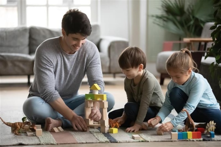 Annual fostering report 1: Image shows a man playing with wooden bricks with a young boy and a girl