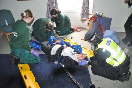 Student paramedics brace the legs of a patient