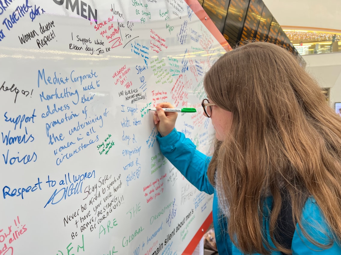 One of many people signing the White Ribbon pledge wall at Birmingham New Street
