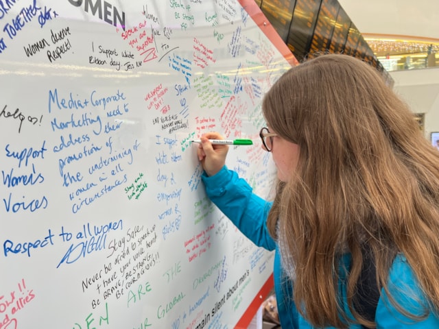 One of many people signing the White Ribbon pledge wall at Birmingham New Street: One of many people signing the White Ribbon pledge wall at Birmingham New Street