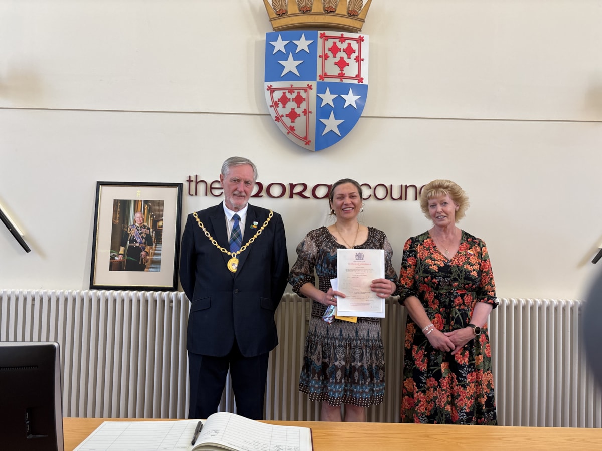 Yana Rabago (Centre) receiving her citizenship certificate from Moray Council Civic Leader Cllr John Cowe and Vice Lord-Lieutenant of Moray, Nancy Robson.