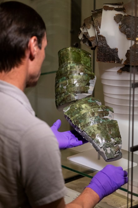 Dr Fraser Hunter installs the Roman arm guard in the Early People gallery at the National Museum of Scoltand. Image copyright Duncan McGlynn (1)