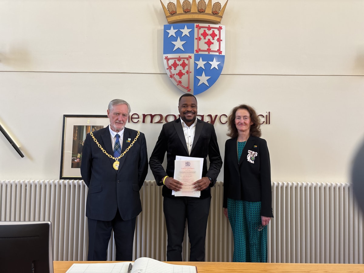 Chukwu Anolue (Centre) receiving his citizenship certificate from Moray Council Civic Leader Cllr John Cowe and Vice Lord-Lieutenant of Moray, Nancy Robson.