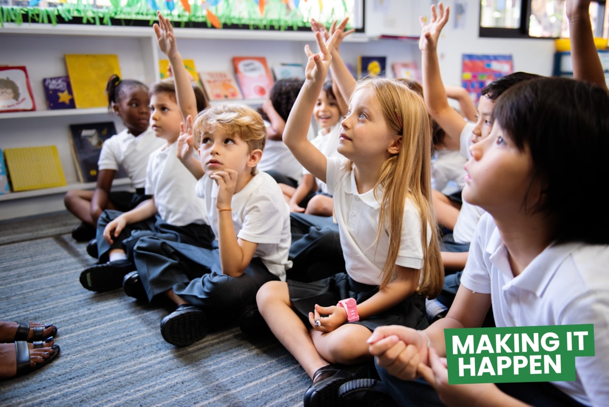 A group of children raising their hands with the 'making it happen' campaign logo