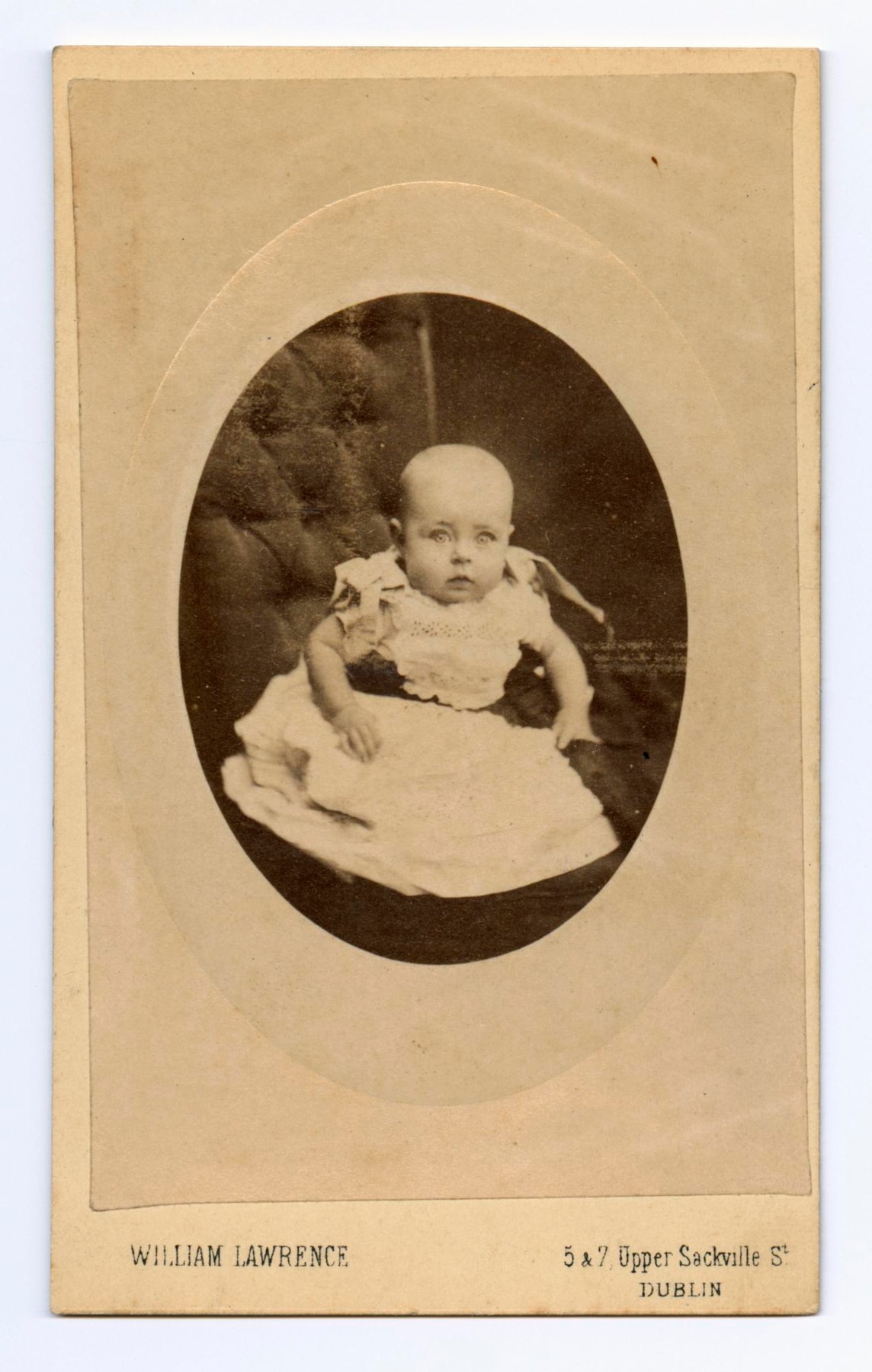 Carte-de-visite depicting unidentified baby, the hands of the mother can just be seen holding the baby round the waist, by William Lawrence, Dublin