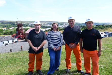 Heledd Fychan yn Big Pit gyda Pennaeth y Safle, Brian Lewis, a dau tywyswyr y Daith Danddaearol, gyda'r Headgear Big Pit yn y cefndir