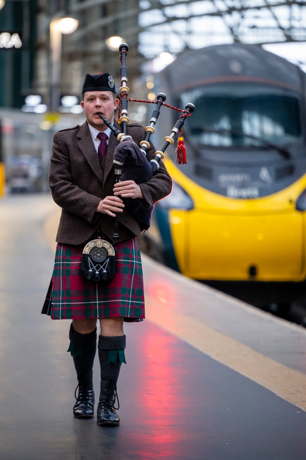 A bagpiper sends off the poppy wreath at Glasgow Central station