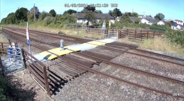Toddler steps onto Sandy Lane level crossing in Prestatyn, North Wales, before accompanying adult is through the gate