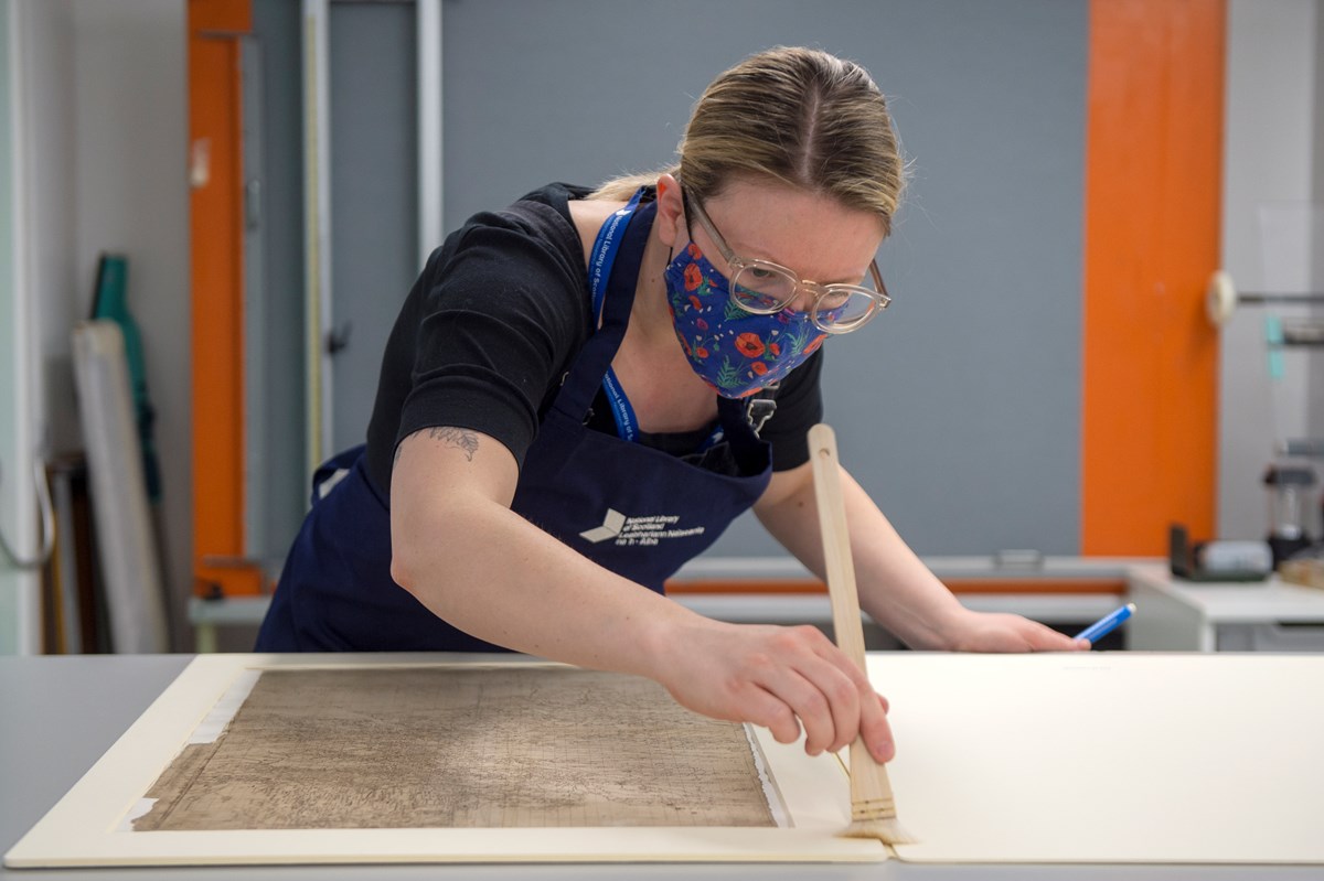 Library Conservator Lizzie Fuller inspects a Timothy Pont map (1596)  - detailing most of the drainage basin of the River Clyde. Credit: Neil Hanna