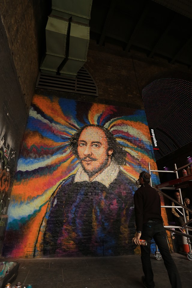Jimmy C wider shot: Street artist Jimmy C works on a portrait of William Shakespeare on a Network Rail wall in Southwark