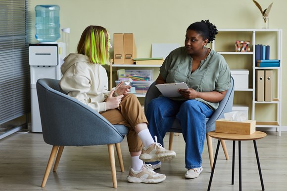 Ofsted rate Hertfordshire County Council’s Children’s Services as ‘Outstanding’: Female social worker talking to teenage girl in an office