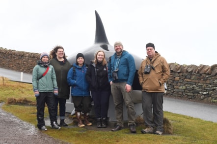 A group of scientists and students stood in front of a killer whale installation on the Shetland Isles.
