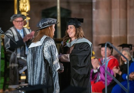 University vice chancellor Professor Julie Mennell in a silver academic robe greets Mental Health Nursing graduate Kelly Cornwell