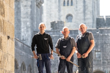 Tri chwarelwr yn sefyll tu allan i Gastell Penrhyn.