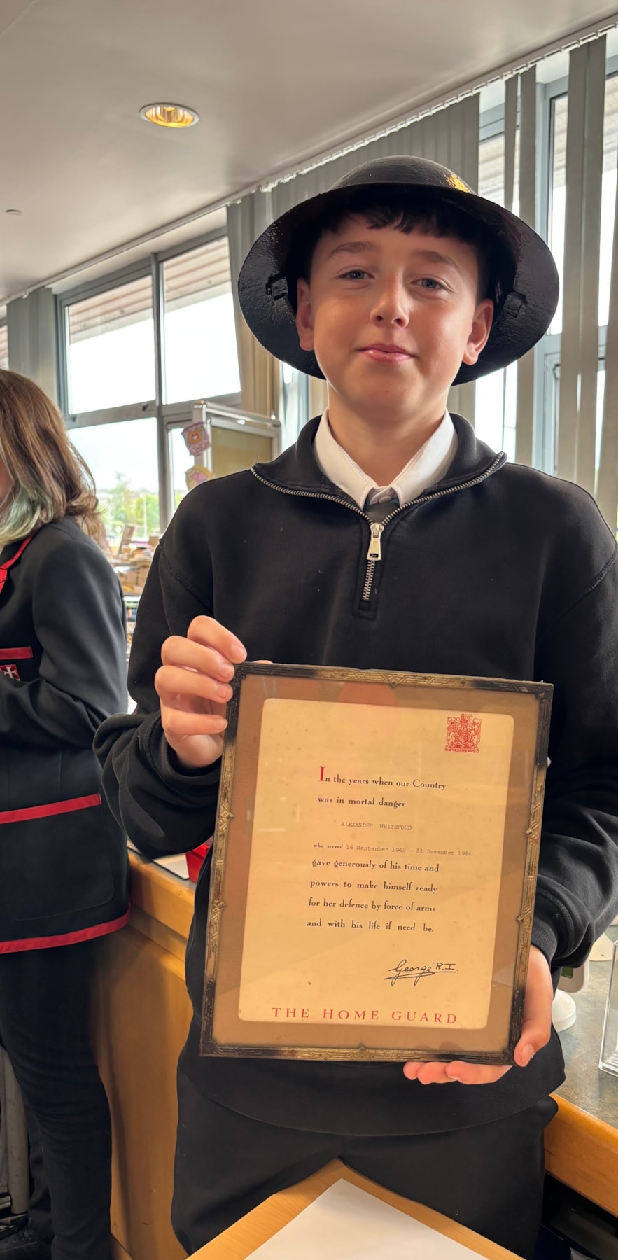 Harry from Stewarton Academy with a certificate presented to his Great Grandfather and wearing his Great Grandfather's helmet
