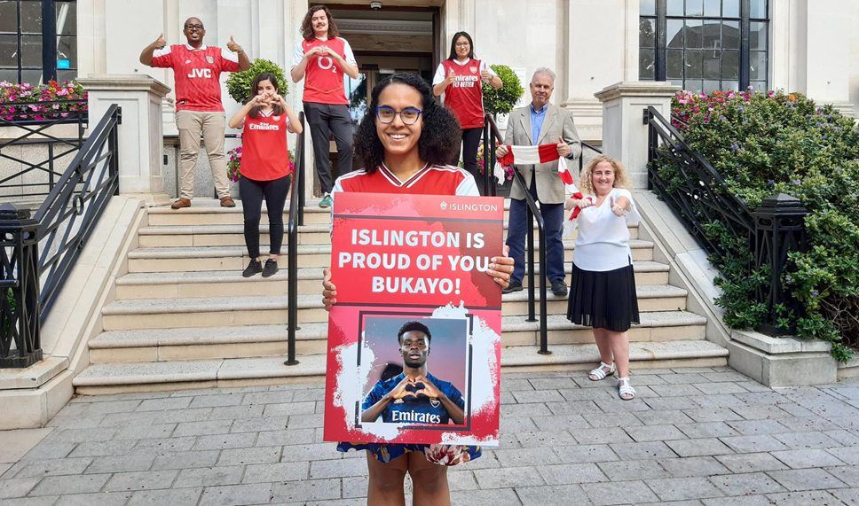 Islington Council leader Cllr Kaya Comer-Schwartz with a card saying "Islington is proud of you, Bukayo!", with  Cllrs Ibrahim, Ozdemir, Bell-Bradford, Khondoker, Convery and O'Halloran in the background