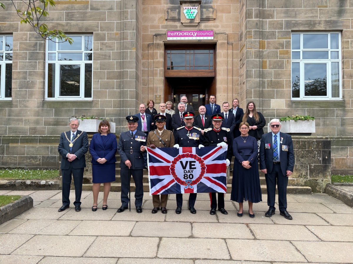 Moray Council elected members, civic leaders and military personnel with the VE Day 80 flag