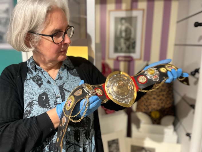 In the Picture: Curator Kitty Ross with a leotard and belt once worn by the city’s own female wrestler Sue Brittain, later known to opponents as Lady Satan.
Outside the ropes the pioneering grappler’s real name was Marjorie Farrar. She lived in Pudsey and throughout her career, fought a series of legal battles to be allowed to compete, including using equal opportunities legislation against the then Greater London Council during a two-day court hearing in 1979.