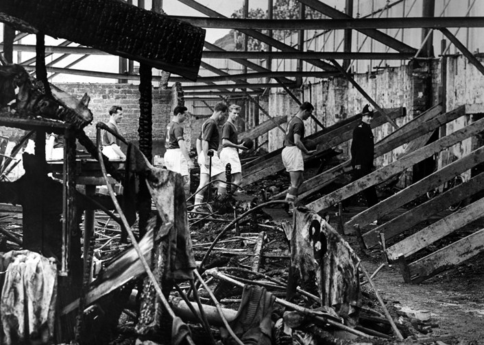 Fire Damage at Elland Road Stadium 1956. Image: © Leeds United Football Club: Members of the 1956 Leeds United Team inspecting the West Stand, which was completely destroyed by fire. Image: © Leeds United Football Club.