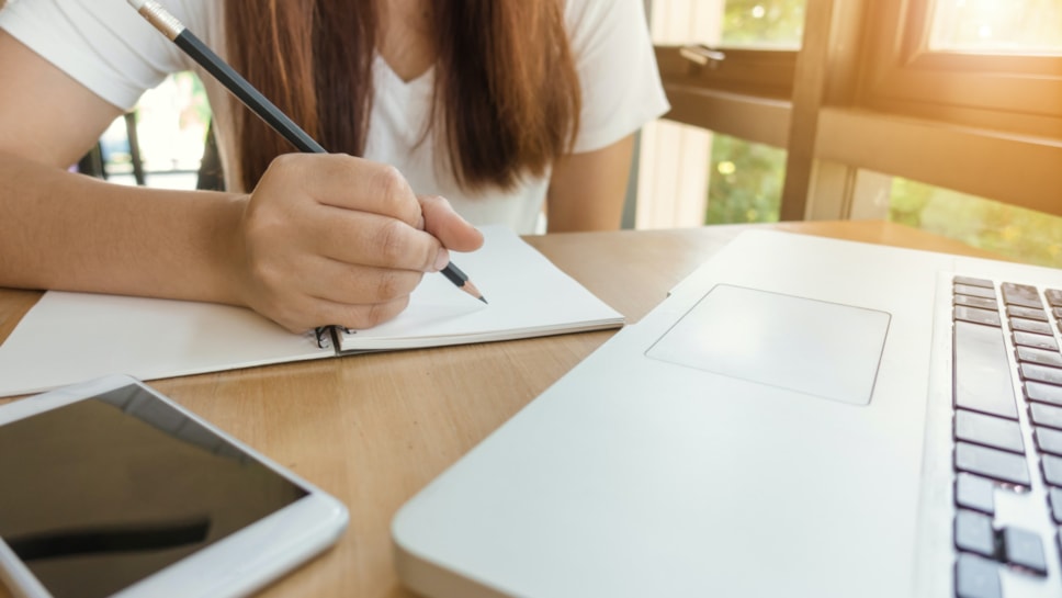 Woman writing by laptop