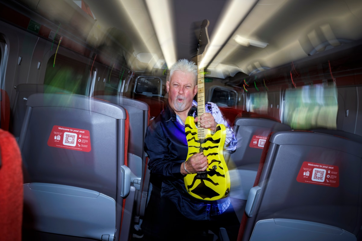 Robb Weir with guitar onboard LNER train