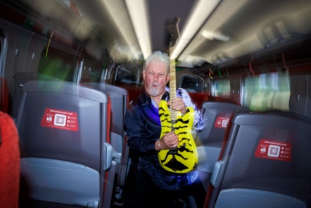 Robb Weir with guitar onboard LNER train