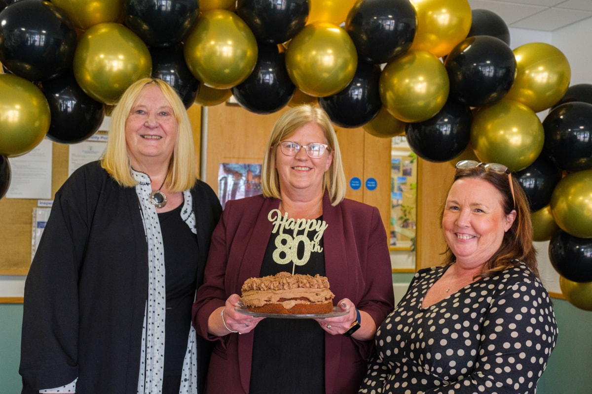 Current Head of Centre Margaret Blades holds a birthday cake along with previous heads Rona Burns and Carol McGregor