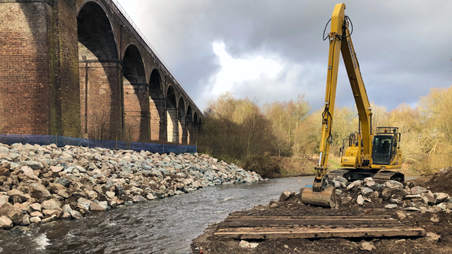 Victorian viaduct river erosion work restarts after major storms: Reddish Vale viaduct with digger to move the 5,500 tonnes of boulders for the river erosion work