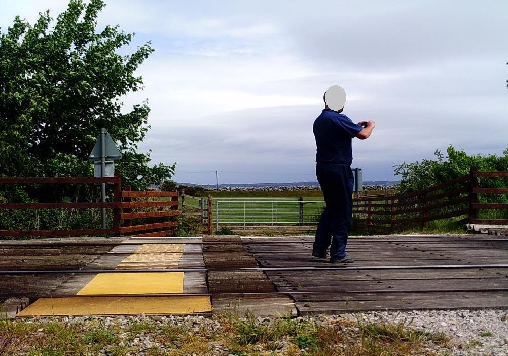 A man leaves the level crossing and stops to take a picture at Stokyn Lodge, Mostyn