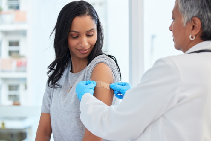 healthcare-worker-applying-bandage: A healthcare worker applying a plaster after vaccinating a patient