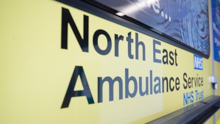 The door of an ambulance displaying the text 'NHS, North East Ambulance Service NHS Trust'.