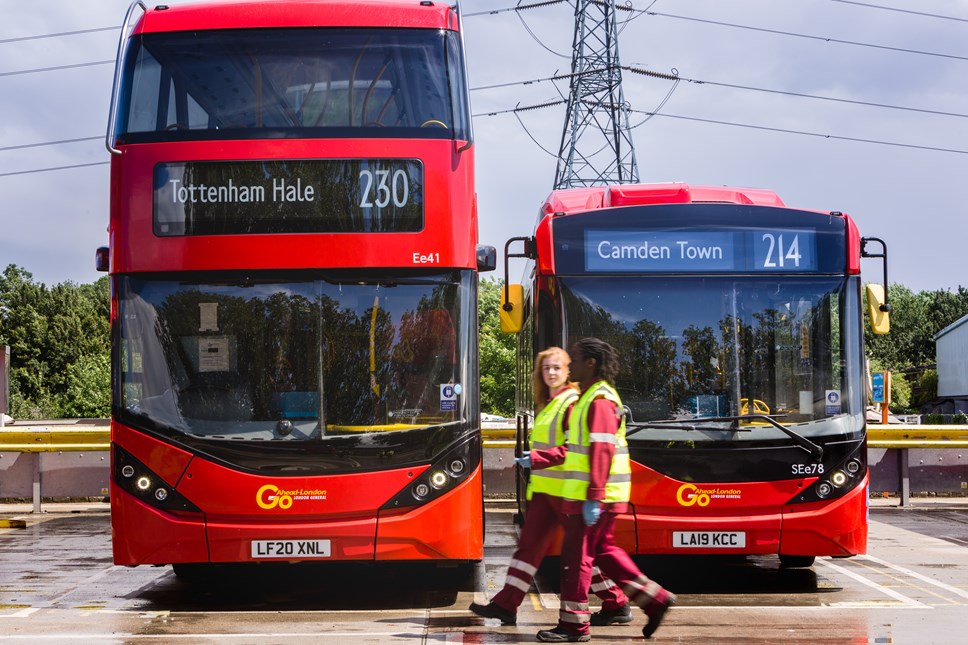 Flora McIlroy and Damani Roberts-Franklin walking in front of electric buses and pylon at Northumberland Park