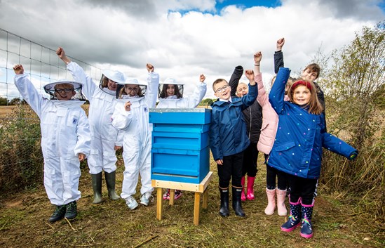 Northants school children celebrate first beehives installed on HS2 wildlife site: Pupils from The Radstone Primary School on the HS2 site with the bee hives
