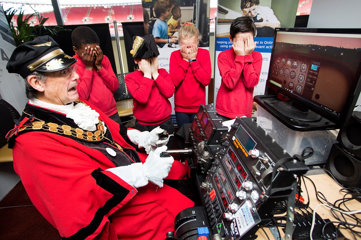 Islington Mayor, Cllr Dave Poyser crashing the flight simulator with children from Tufnell Park Primary School covering their eyes