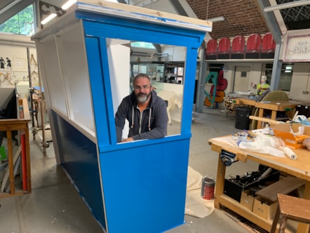 University of Cumbria Ed Cooper stood inside a recreated wooden commentary box in a workshop on campus