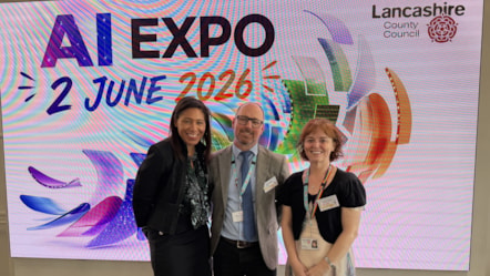 Two women and a man with glasses standing in front of screen that says AI EXPO 2 June 2026 with Lancashire County Council logo above them