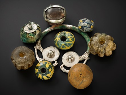 Beads, curios, and heirloom objects were bundled and strung together resting as a group on a silver brooch-hoop at the top of the lidded vessel in the Galloway Hoard