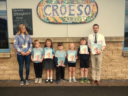 Acting Headteacher Ross Williams and pupils at Johnston CP School receive book donations from the Community Benefits scheme.