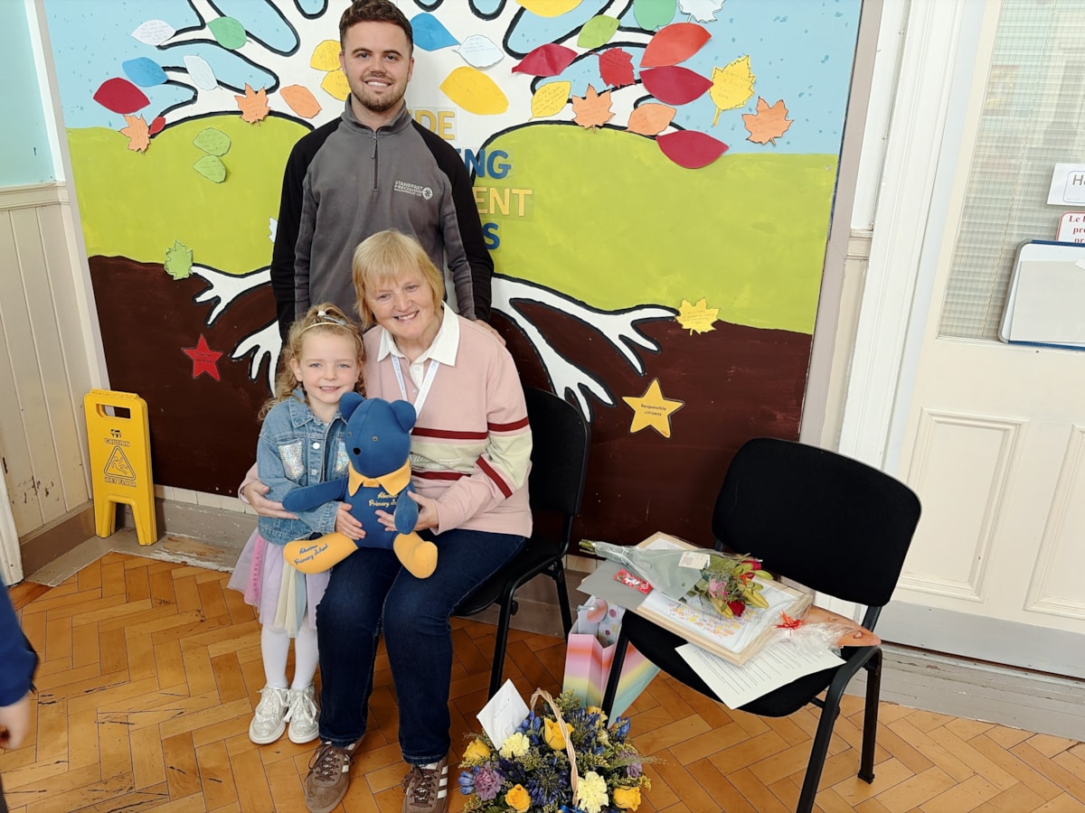 Hester Allan is presented with retirement gifts, after 26 years of service to Aberlour Primary School, by former pupil Greig Donald and current P1, Aila Walker.