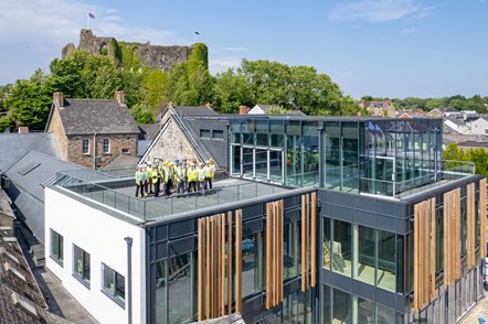 Drone shot of group of senior council and construction staff on roof terrace of Western Quayside with Haverfordwest castle in the background