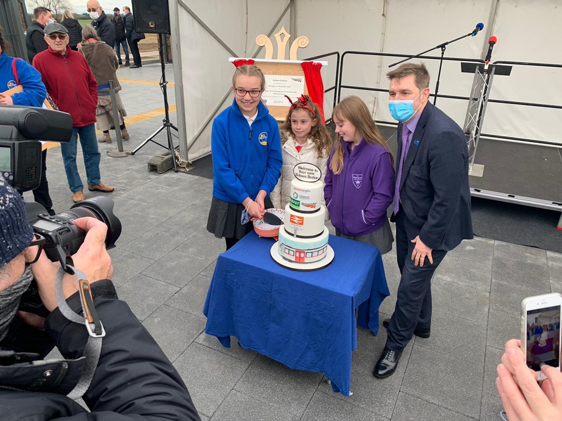 13.12.21 Mayor Dr Nik Johnson Soham station cake cutting with local school children: Winner and runners up of the children's station poster competition, cutting the Soham station celebration cake with Mayor Dr Nik Johnson