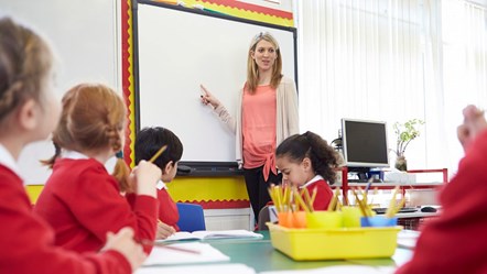 Teacher pointing at board in a primary school class.