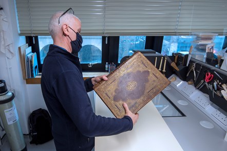 Library Conservator David Kerr inspects the Library's copy of the Gutenberg Bible before it is installed at the Treasures of the National Library exhibition. Credit: Neil Hanna