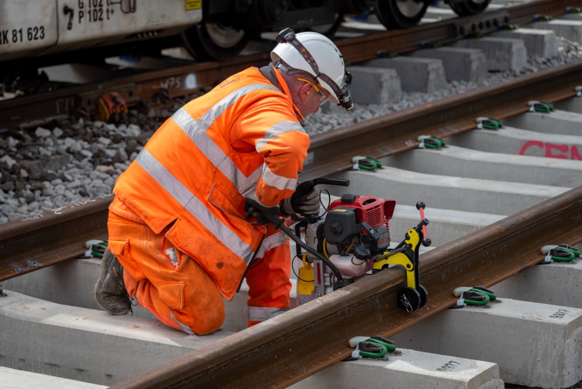 Warrington - Dallam Junction engineer drilling holes into rail for equipment fixings
