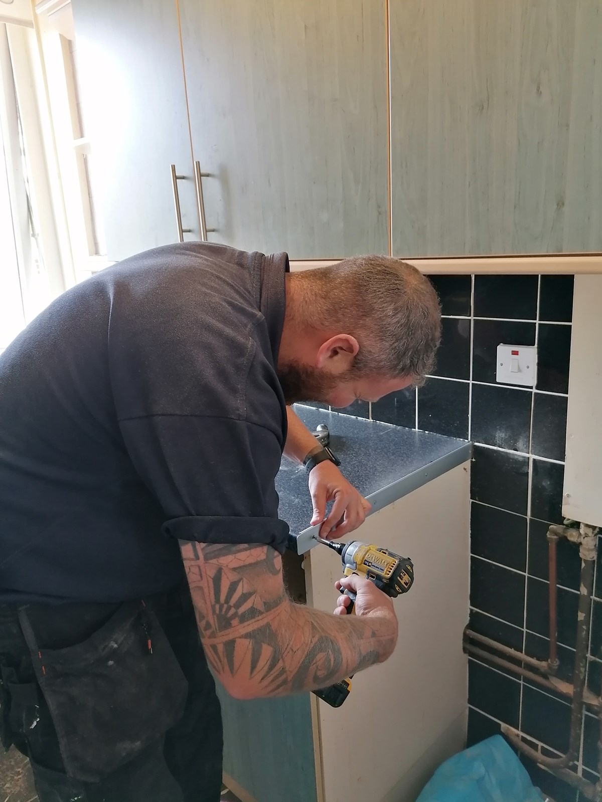 Adult Apprentice Ryan Gillon pictured using a drill to secure a kitchen worktop