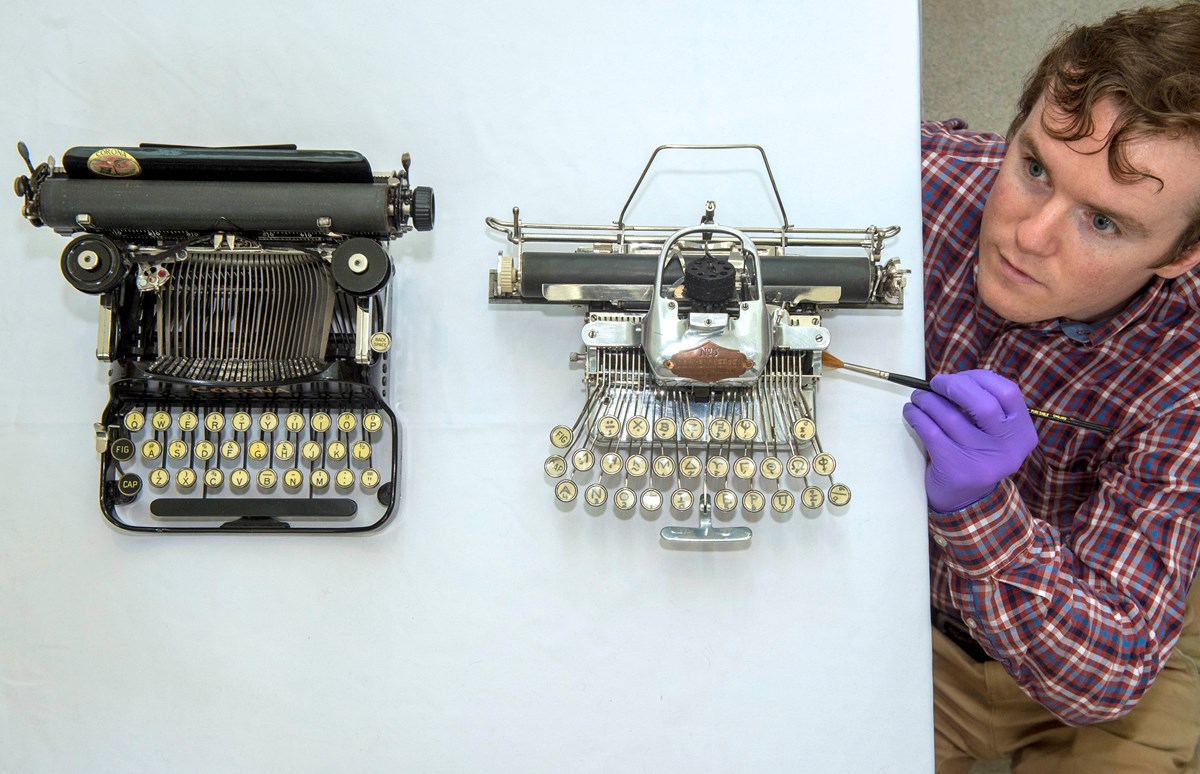 PhD student James Inglis with two of the typewriters featured in the exhibition. Photo © Neil Hanna