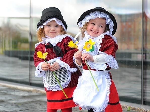 Two girls in Welsh costumes holding daffodils celebrating St. David's Day
